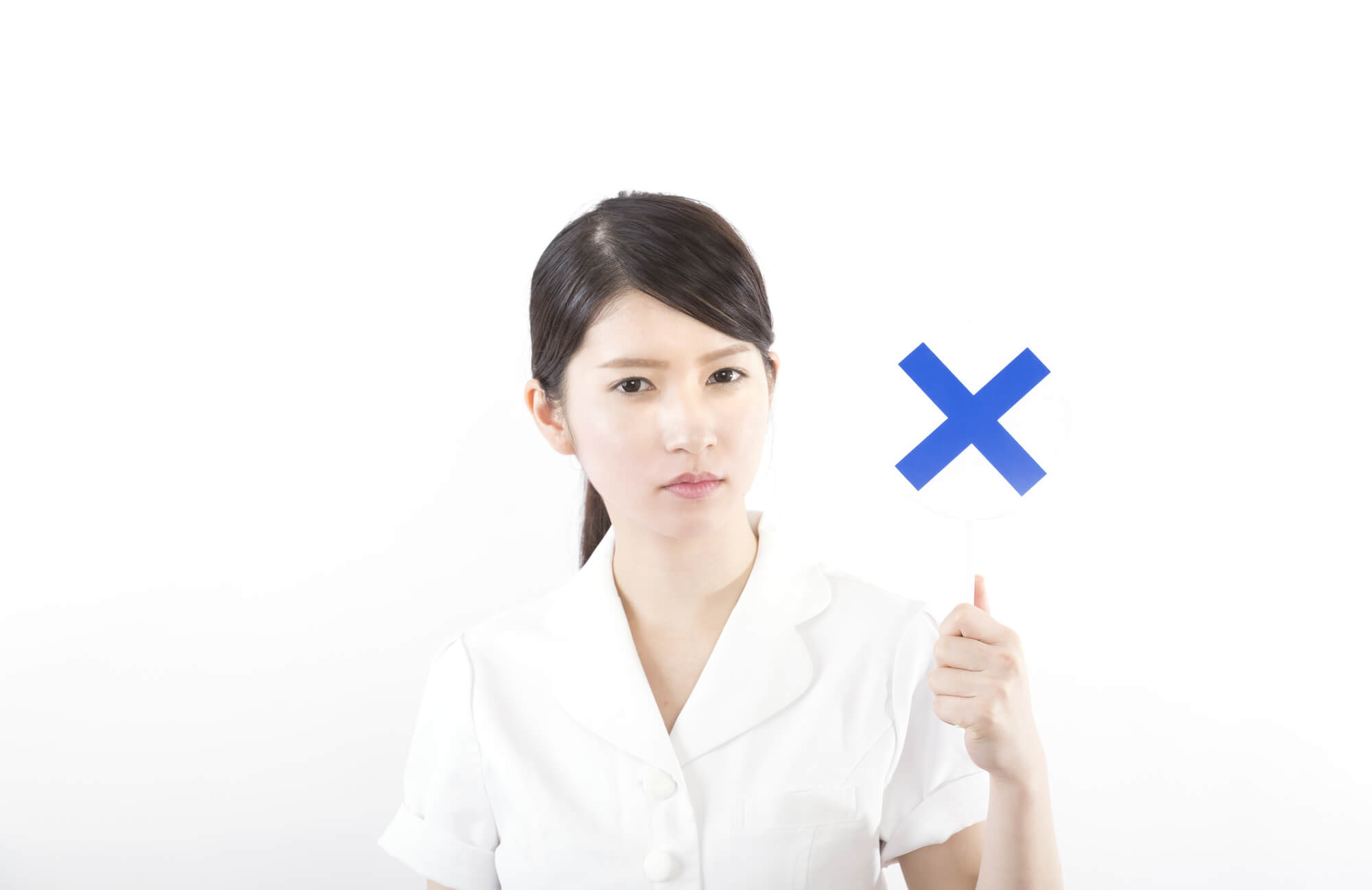 ✕を掲げるナースの女性
